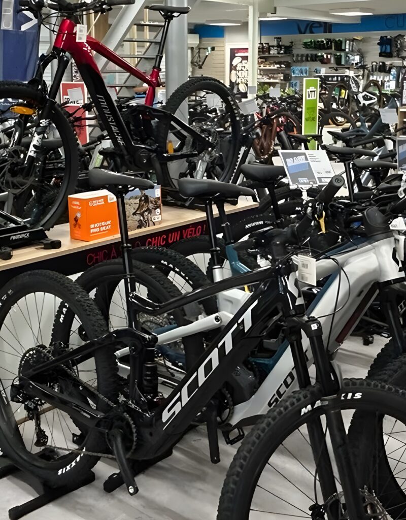Vélos VTT Électriques SCOTT et MOUNTAIN en Magasin Intérieur d'un magasin de vélos : vélos VTT électriques SCOTT et MOUNTAIN, pneus MAXXIS, slogan "CHIC UN VÉLO!"