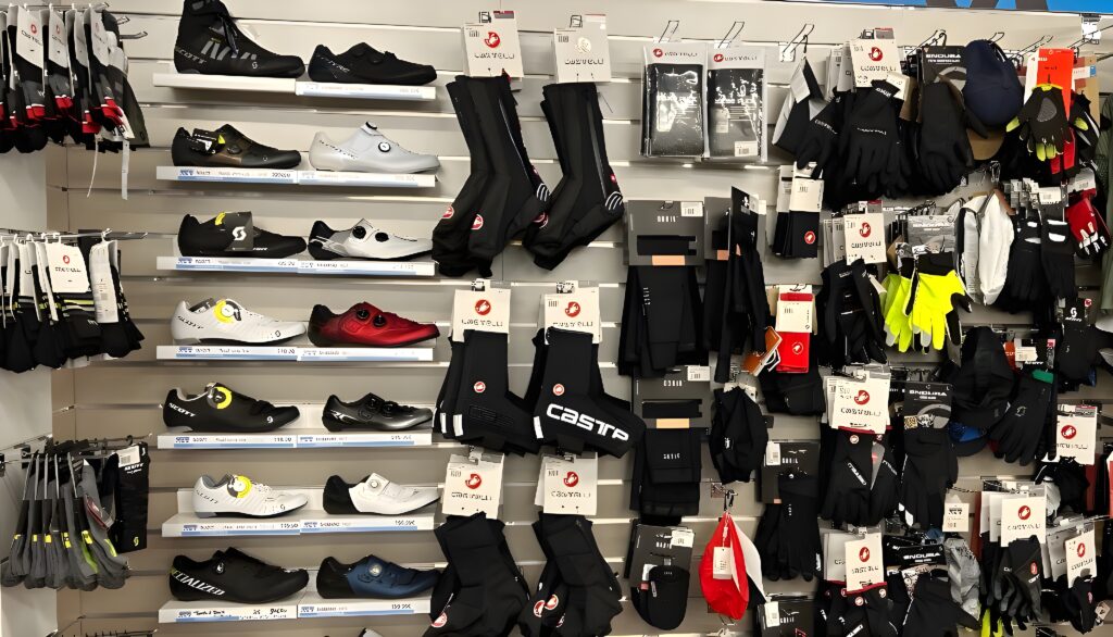 Vêtements et chaussures de cyclisme : Castelli, Scott Présentoir de magasin avec chaussures de vélo, bottes de cyclisme Scott, surchaussures Castelli, gants assortis et accessoires de cyclisme.